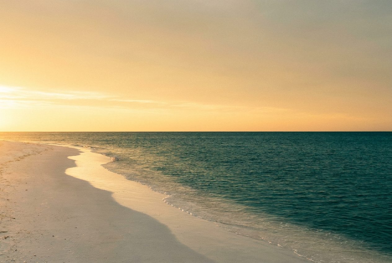Dawn light breaking over a calm gulf horizon from a quiet shoreline